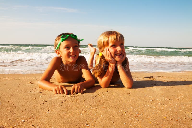 Two happy children on beach, sea in background.