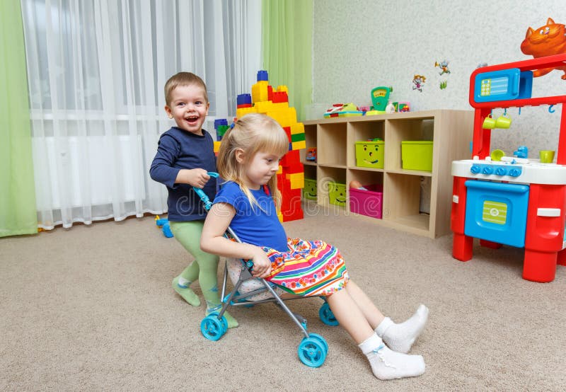 Two happy children play with toy stroller in daycare stock photography Two happy children play with toy stroller in daycare stock photography