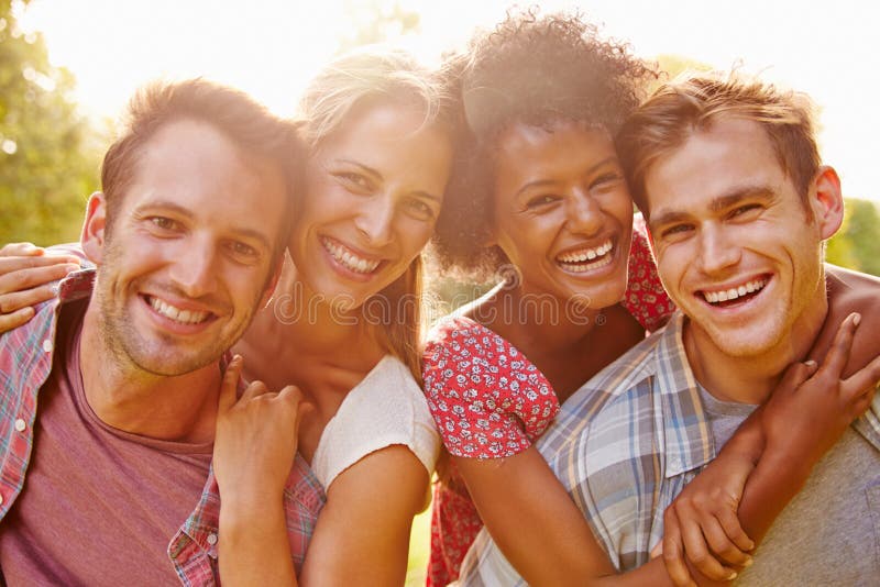Two happy couples embracing and smiling to camera outdoors stock images