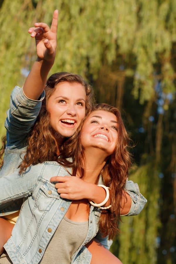 Girl giving her friend a piggyback ride stock photo