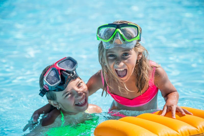 Two happy girls playing in the pool on a sunny day. Cute little girls enjoying holiday vacation