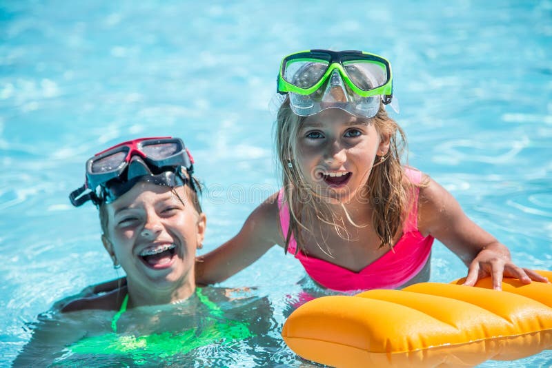 Two happy girls playing in the pool on a sunny day. Cute little girls enjoying holiday vacation