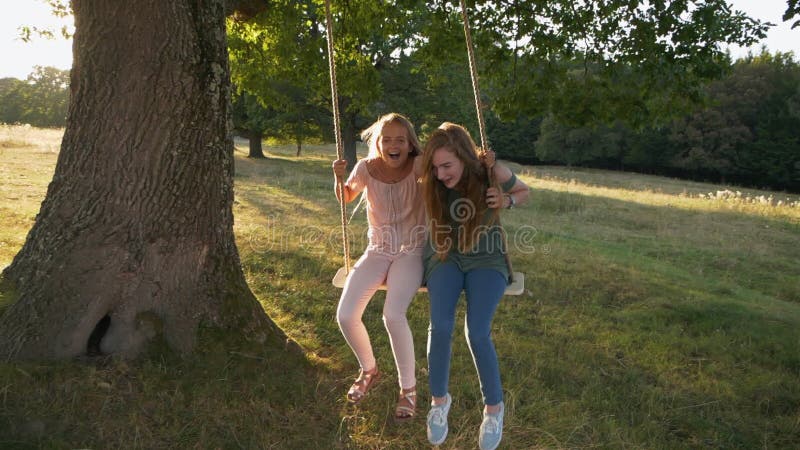 Two happy girls on rope swing - slow mo