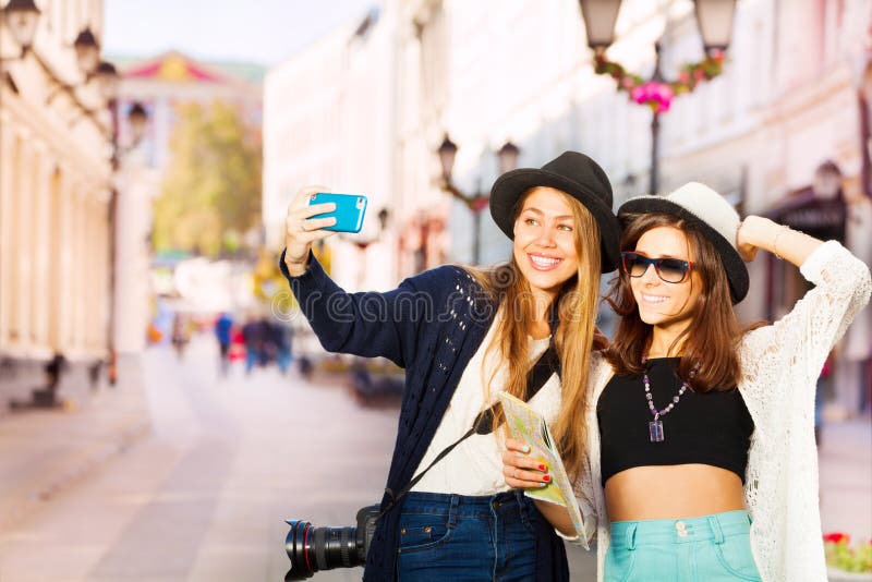 Two happy girls taking selfies with mobile phone