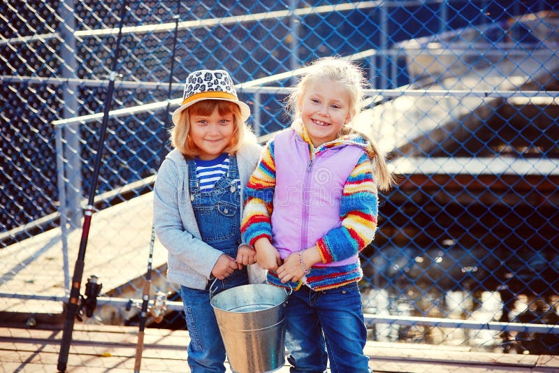 Two happy laughing children with fishing rods and a bucket on a stock images Two happy laughing children with fishing rods and a bucket on a stock images