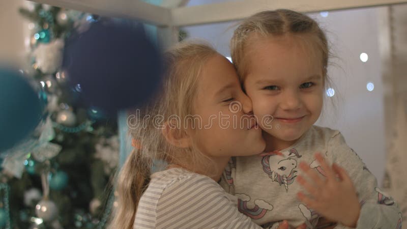 Two happy little girls smile and laugh near Christmas tree