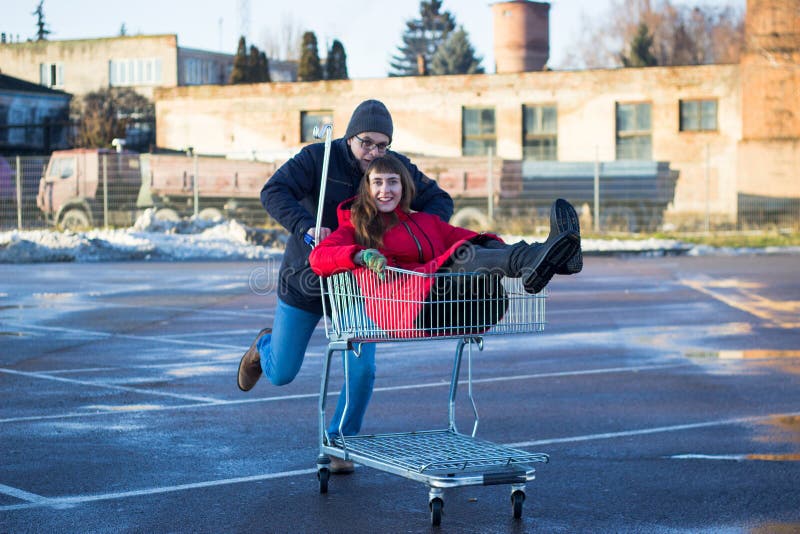 Two happy man and woman having fun at shopping cart outdoors stock photos Two happy man and woman having fun at shopping cart outdoors stock photos