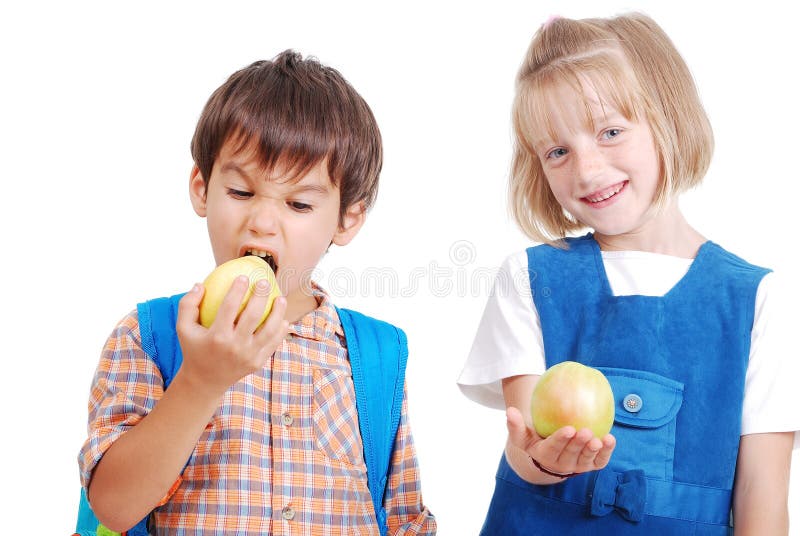 Two happy school children eating an apple