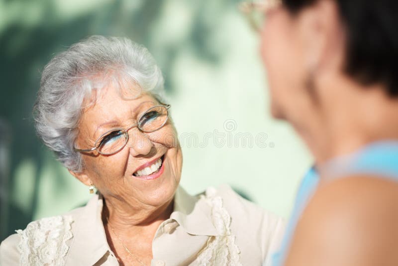 Two happy senior women talking in park stock photos Two happy senior women talking in park stock photos