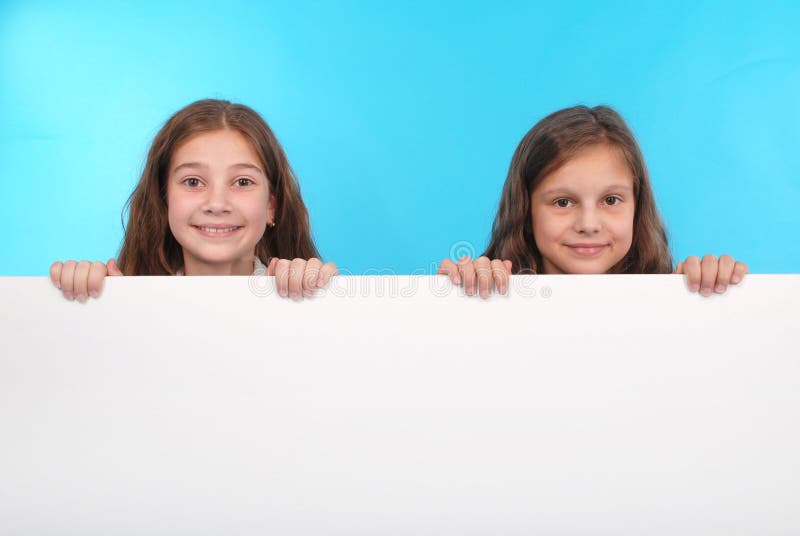 Two happy smiling beautiful young girl showing blank signboard or copyspace for slogan or text stock photo Two happy smiling beautiful young girl showing blank signboard or copyspace for slogan or text stock photo