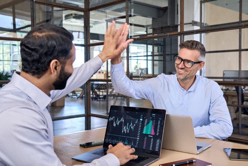 Two happy successful diverse traders investors giving high five.