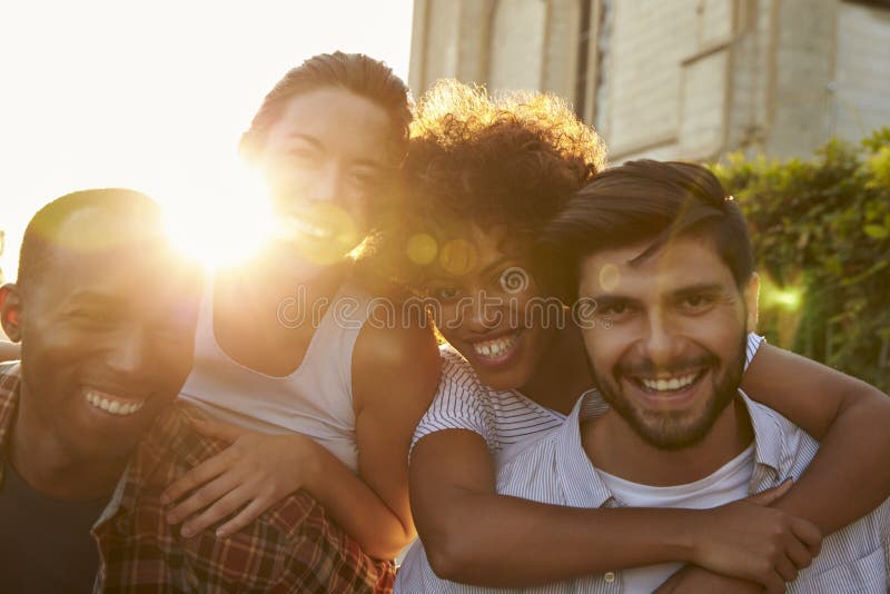 Two happy young adult couples piggybacking the street stock image Two happy young adult couples piggybacking the street stock image
