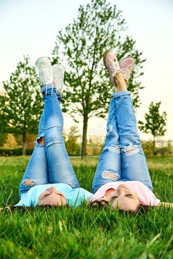 Two Happy Young Girls Lie on the Grass Stock Photo - Image of brunette ...