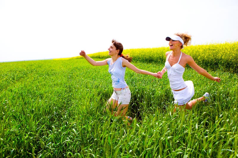 Two happy young women are runing in a field stock photo Two happy young women are runing in a field stock photo