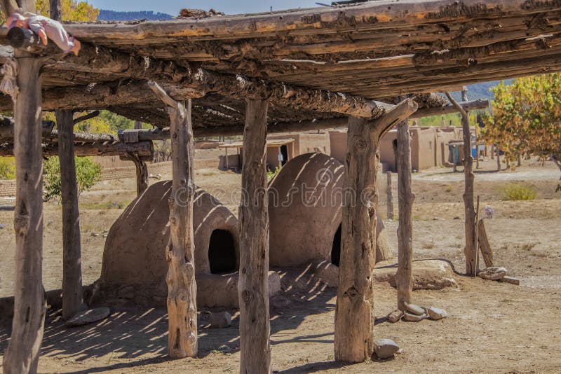 Two hornos-traditional earthen ovens- underneath a drying rack with a childs doll left on the corner - Homes of the Ute Pueblo in