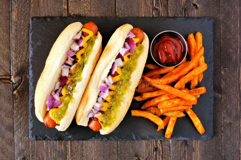 Hot dogs with onions, relish, mustard and ketchup served with fries, top view