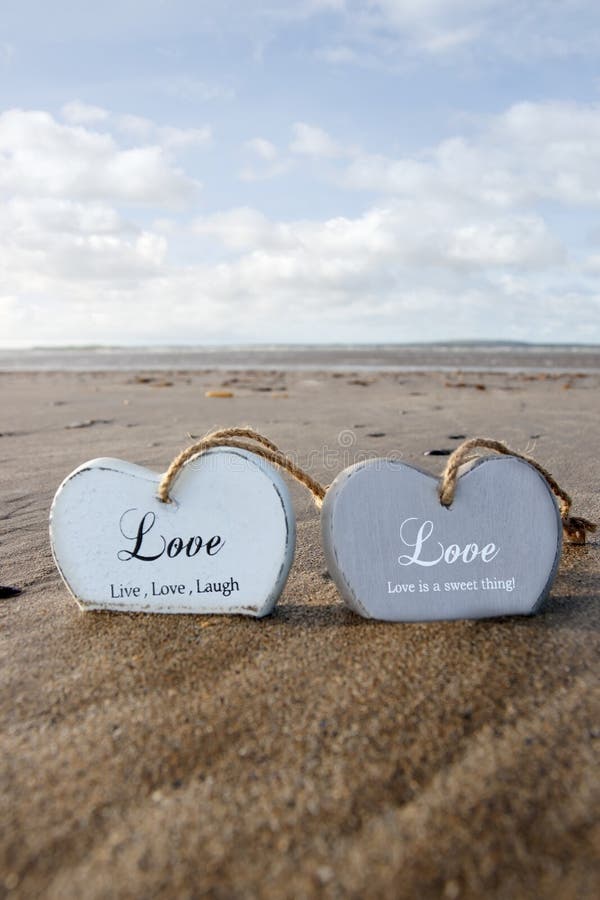 Two inscribed wooden love hearts in the sand