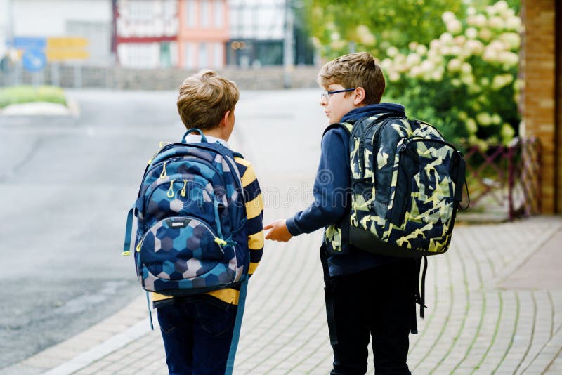 Two kid boys with backpack or satchel. Schoolkids on the way to school. Healthy smiling children, brothers and best