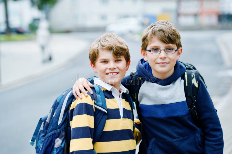 Two kid boys with backpack or satchel. Schoolkids on the way to school. Healthy smiling children, brothers and best