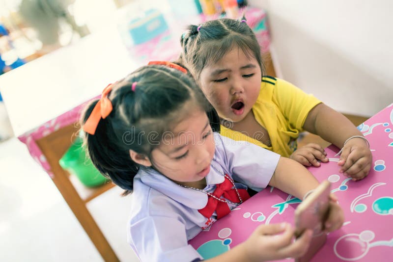 two kid girls play mobile phone after school stock photo two kid girls play mobile phone after school stock photo