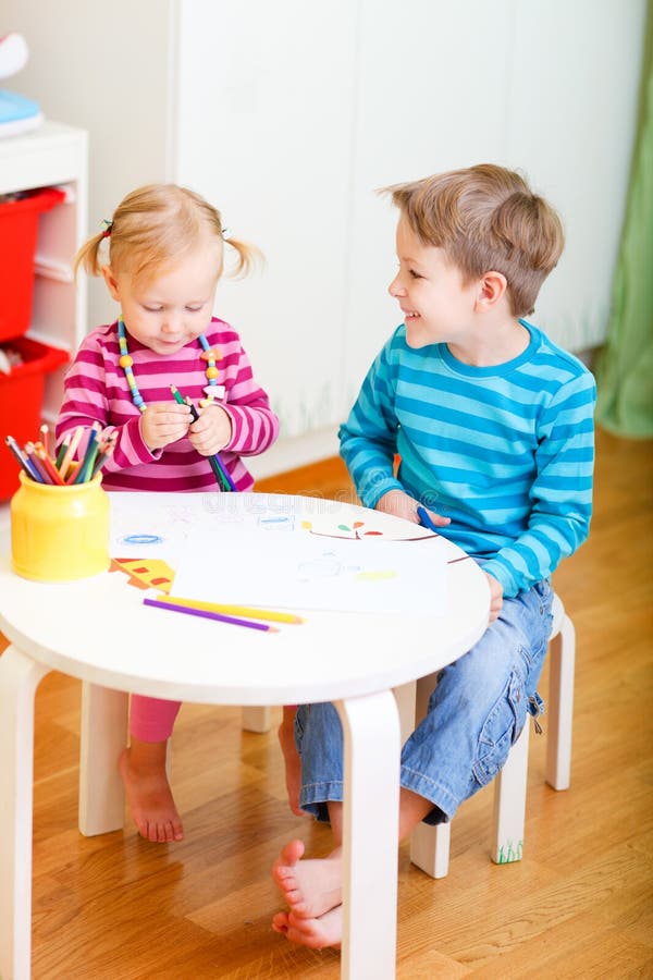 Vertical photo of two small kids drawing together at their room. Vertical photo of two small kids drawing together at their room