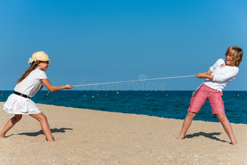 Two kids having a tug war on the beach. Two kids having a tug war on the beach.