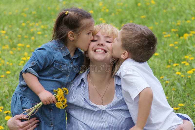 Two kids kissing mother on cheek