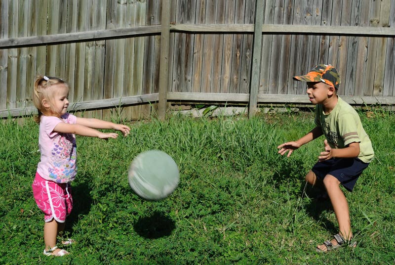 Two kids playing ball in a backyard