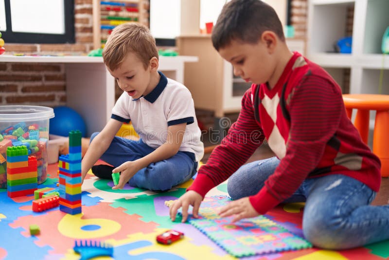Two Kids Playing with Construction Blocks and Maths Puzzle Game Sitting on Floor at Kindergarten
