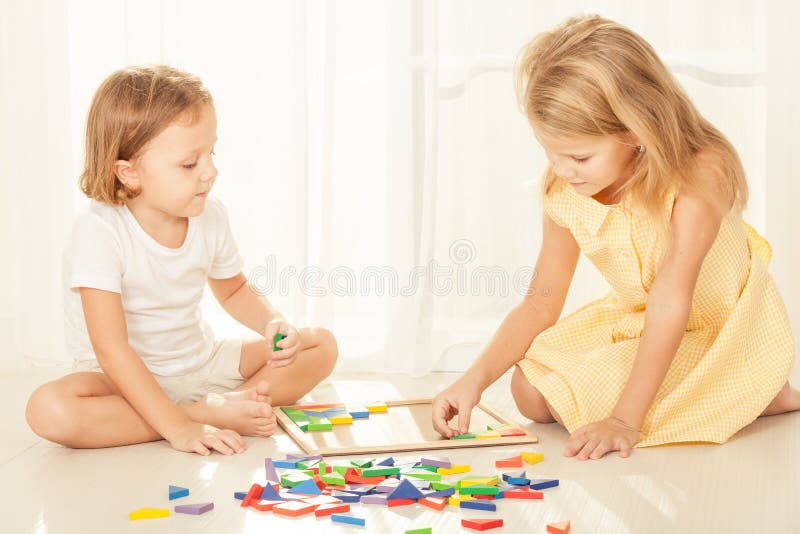 Two kids playing with wooden mosaic in their room