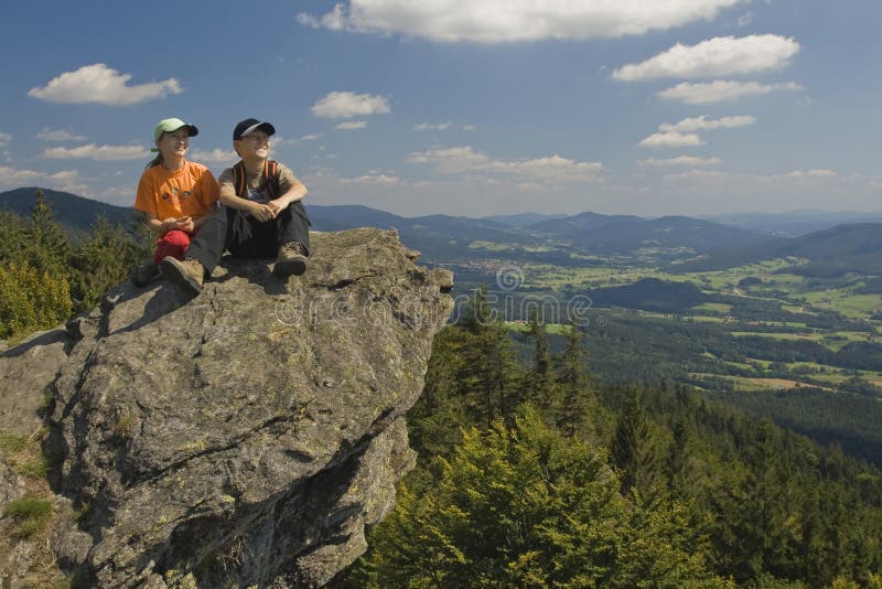 Two kids sitting on a rock in mountains stock photo Two kids sitting on a rock in mountains stock photo