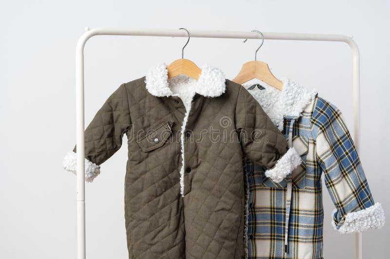 Two Kids Winter Coats Hanging on Hangers Against White Wall Stock Image