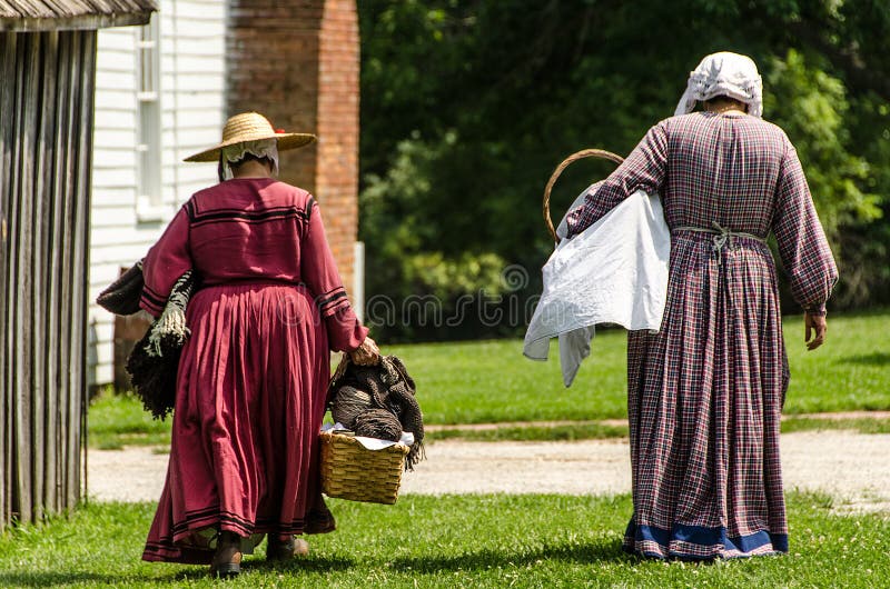 Two ladies / women walking home in colonial dress.