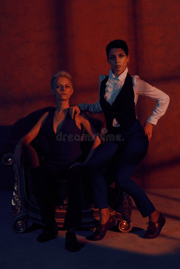 Two lesbians with serious look in old armchair