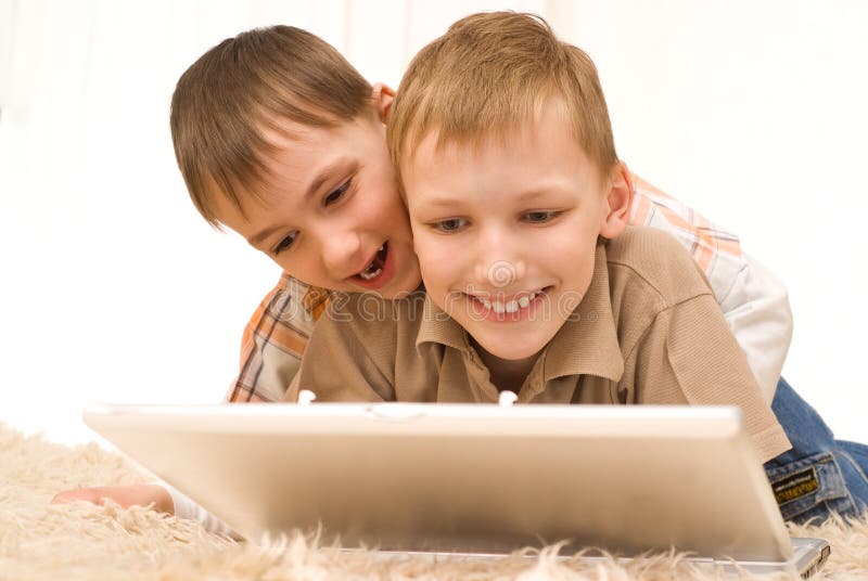 Two little brothers lie with laptop