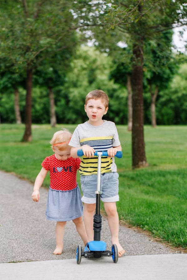 Two little Caucasian preschool children fighting in park outside. Boy and girl can not share one scooter. stock photo Two little Caucasian preschool children fighting in park outside. Boy and girl can not share one scooter. stock photo