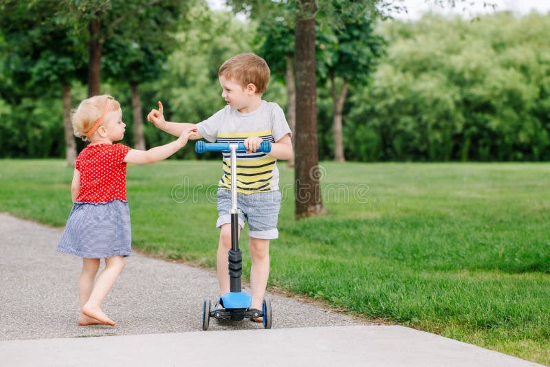 Two little Caucasian preschool children fighting in park outside. Boy and girl can not share one scooter. stock images Two little Caucasian preschool children fighting in park outside. Boy and girl can not share one scooter. stock images