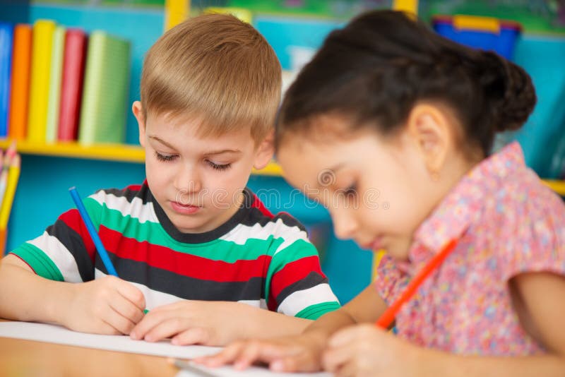 Two little children drawing at kindergarten stock images