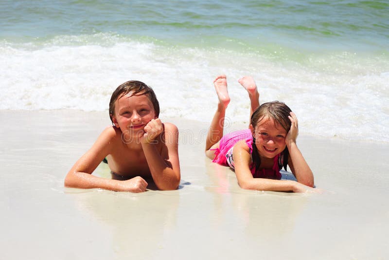 Two little children resting on beach and smiling