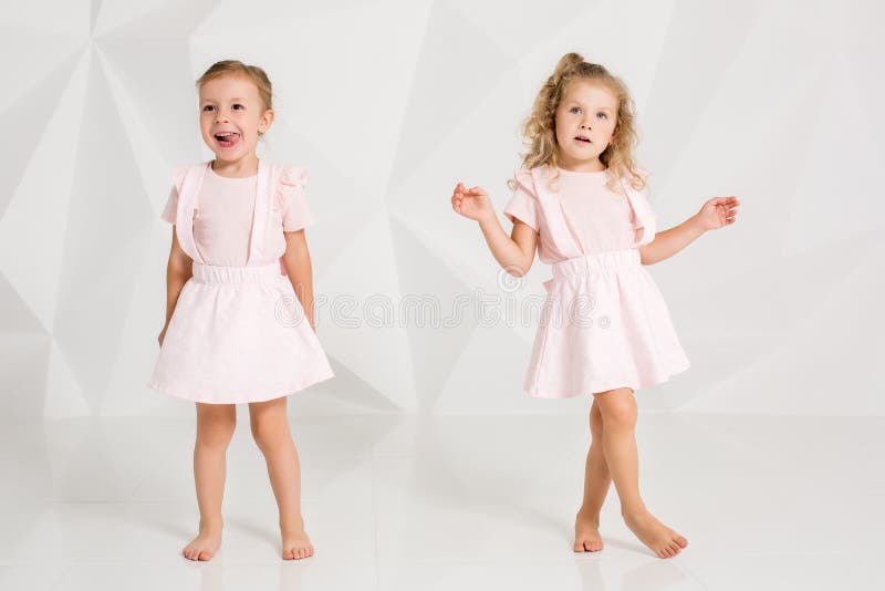 Two little funny and laughing girl in gently pink dresses posing in white studio royalty free stock photos Two little funny and laughing girl in gently pink dresses posing in white studio royalty free stock photos