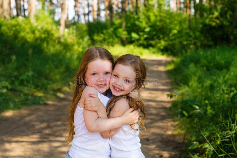 Two little girl girl friends hugging in the forest