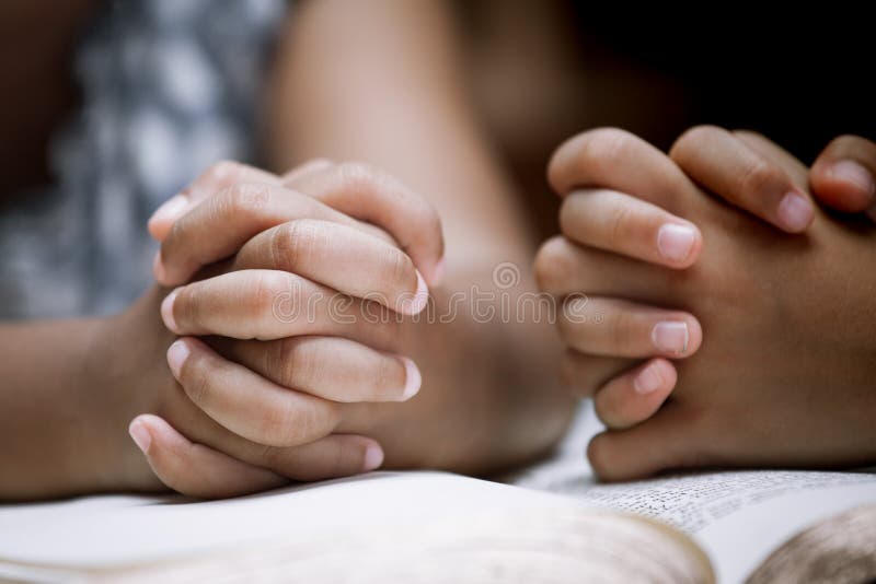 Two Little girl hands folded in prayer on a Holy Bible