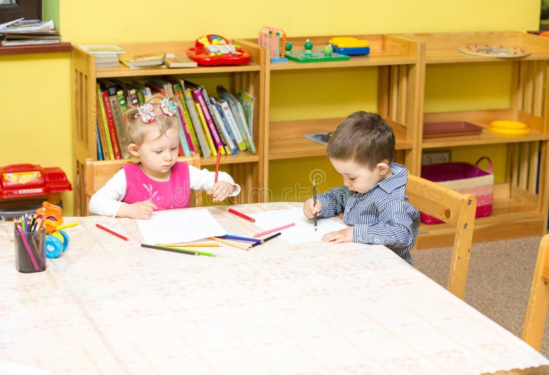 Two little kids drawing with colorful pencils in preschool at the table. girl and boy drawing in kindergarten