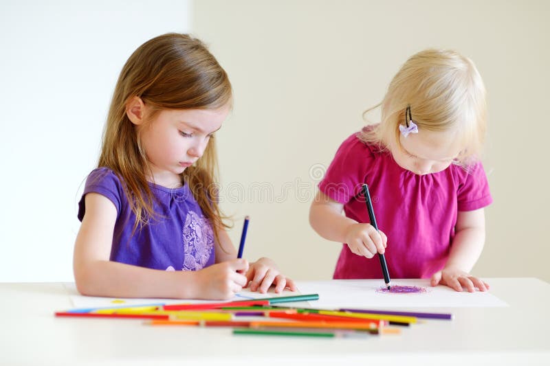 Two little sisters drawing with colorful pencils