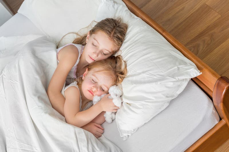 Retrato de dos hermanas jugando en la cama - En casa, etnia caucásica - Stock Ph