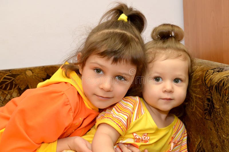 Two little sisters sit on a sofa. Portrait royalty free stock photos Two little sisters sit on a sofa. Portrait royalty free stock photos
