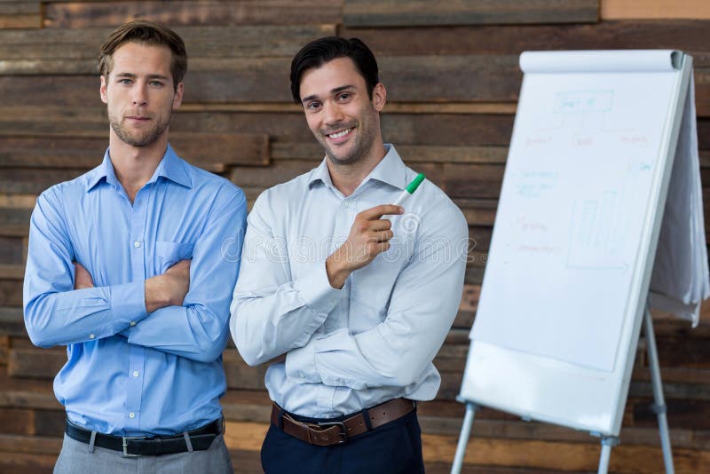 Two Male Business Executives in a Meeting Standing in Front of a Flip
