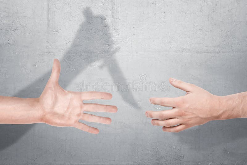 Two male hands getting close for a handshake with a shadow of one hand holding a knife on a concrete background. stock image Two male hands getting close for a handshake with a shadow of one hand holding a knife on a concrete background. stock image