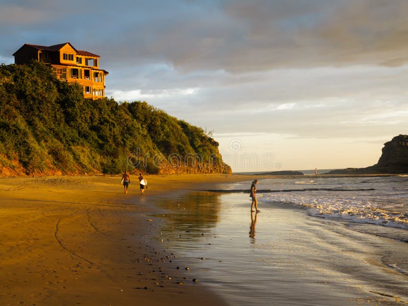 Two male surfers walk on beach carrying surfboards in Nicaragua at low tide