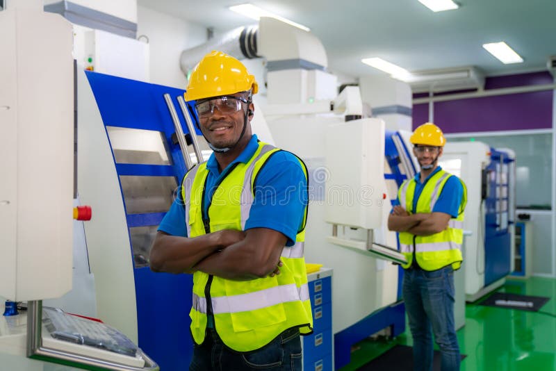 Two mechanical technician operative arm crossed in front of cnc milling cutting machine at factory at tool workshop in metal